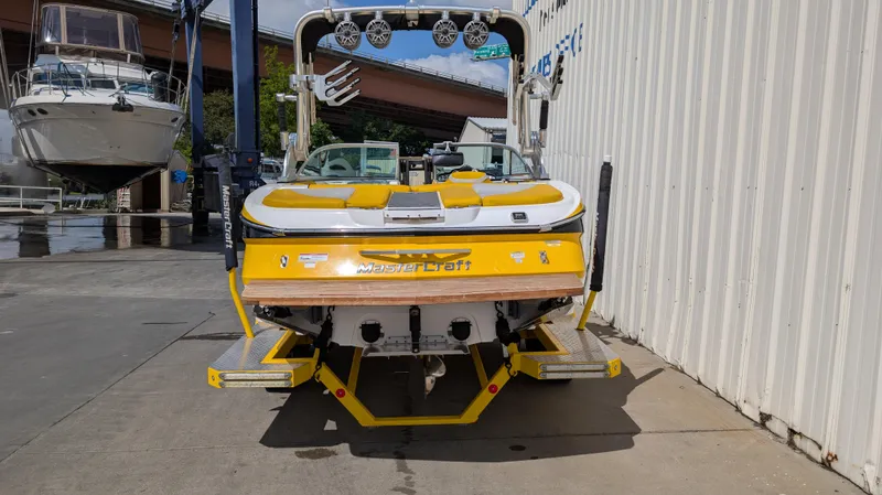 Slide: The Image of 2013 MasterCraft X2 boat, yellow, docked beside a building, rear view. - 4
