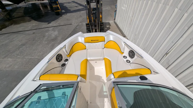 Slide: The Image of 2013 MasterCraft X2 boat with yellow and white seating, docked near a warehouse. - 7
