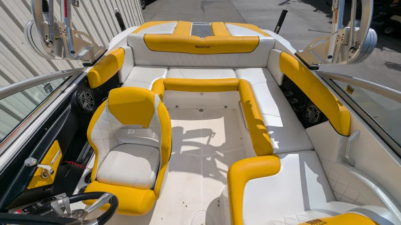 Slide: The Image of 2013 MasterCraft X2 boat interior with yellow and white seating, steering wheel, and speakers. - 9