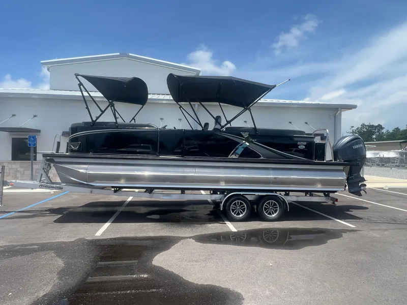 Slide: The Image of 2025 Tahoe LTZ QL25T pontoon boat on trailer, parked outdoors. - 26