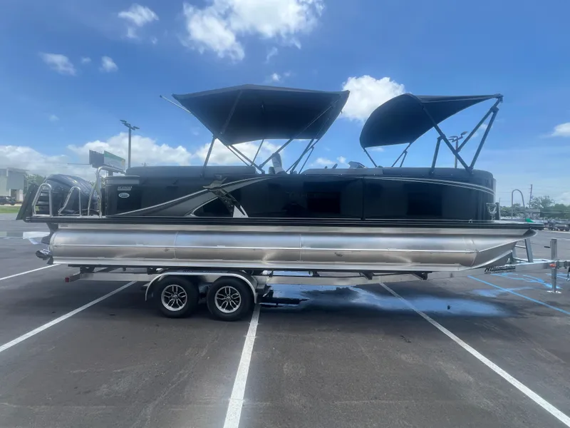 Slide: The Image of 2025 Tahoe LTZ QL25T pontoon boat on trailer under blue sky. - 27