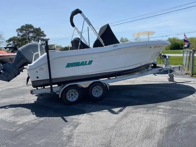 Slide: The Image of 2019 Robalo R200 Center Console boat on a trailer, parked outdoors. - 0