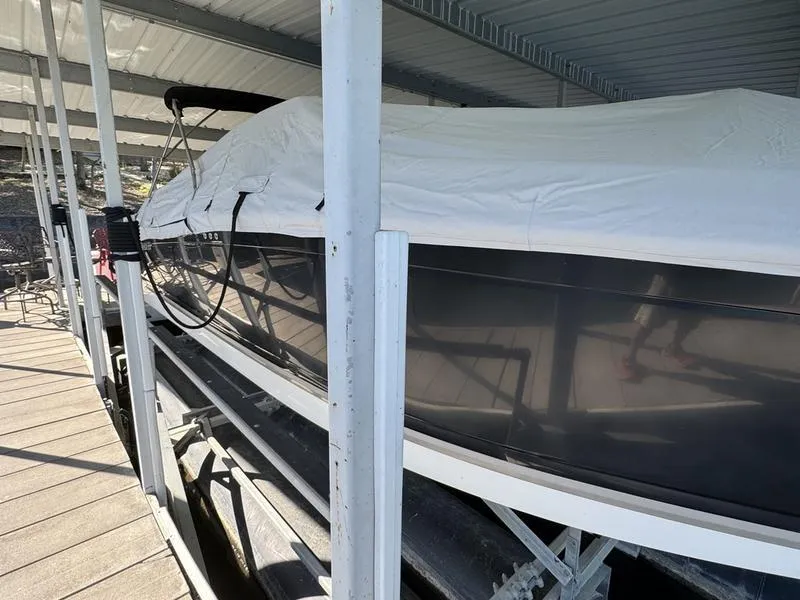 Slide: The Image of 2010 Cobalt 302 boat interior with beige seating and brown accents, docked by a lakeside. - 13