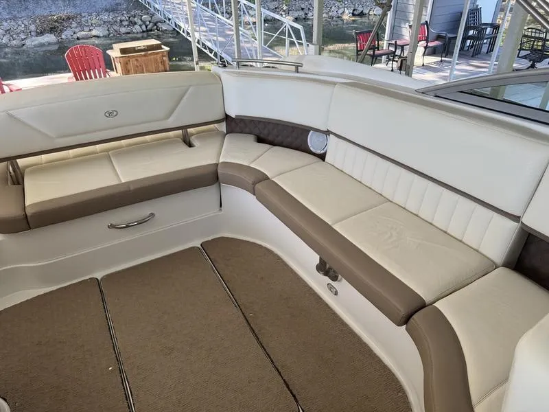 Slide: The Image of 2010 Cobalt 302 boat with beige seating, dockside with red chairs and table. - 16