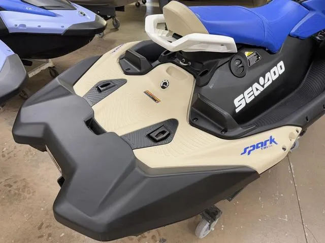 Slide: The Image of 2025 Sea-Doo Spark Trixx Waverunner, blue seat, beige and black body, in showroom. - 5