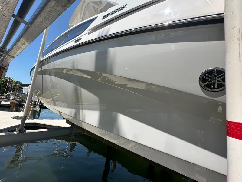 Slide: The Image of 2023 Yamaha Boats 275 SDX on a lift, reflecting sunlight on the water. - 14