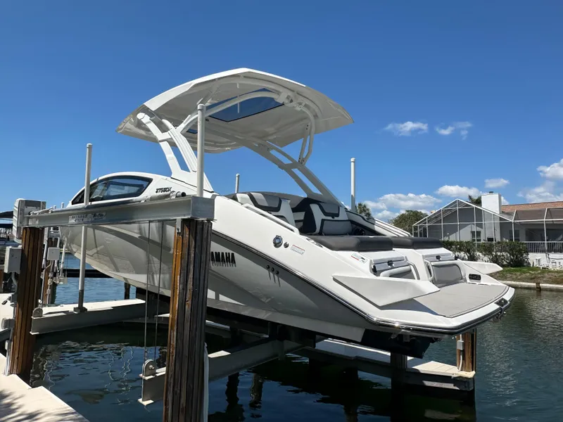 Slide: The Image of 2023 Yamaha Boats 275 SDX on lift, sleek design, sunny day, waterfront setting. - 15