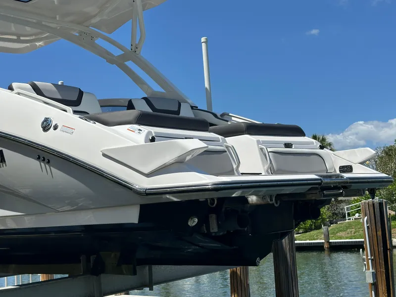 Slide: The Image of 2023 Yamaha Boats 275 SDX on lift, sleek design, dual seating, sunny day, waterfront view. - 17