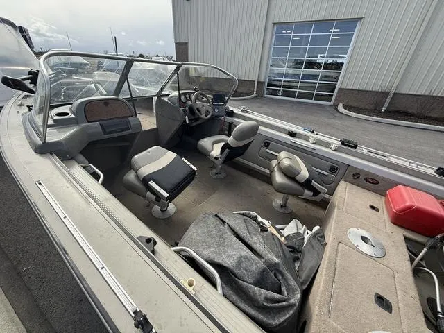 Slide: The Image of 2002 Tracker 185 Targa boat interior with seating and steering wheel, parked outside a building. - 4
