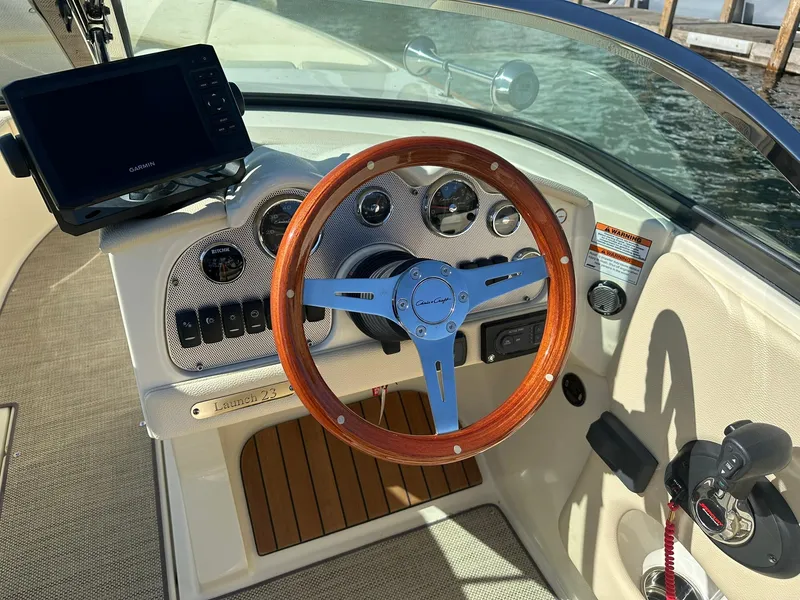 Slide: The Image of 2022 Chris-Craft Launch 23 dashboard with wooden steering wheel and Garmin display. - 13