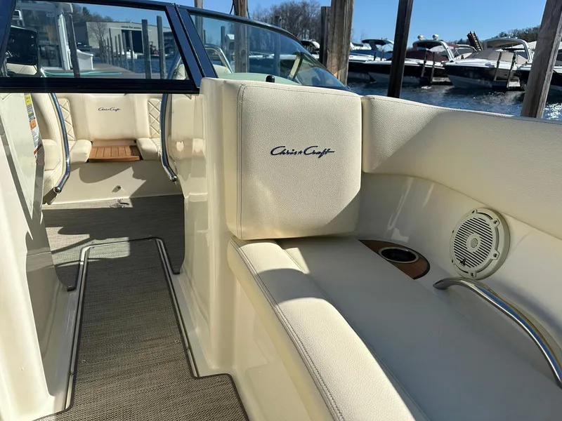 Slide: The Image of 2022 Chris-Craft Launch 23 interior with beige seating and speaker, docked at marina. - 17