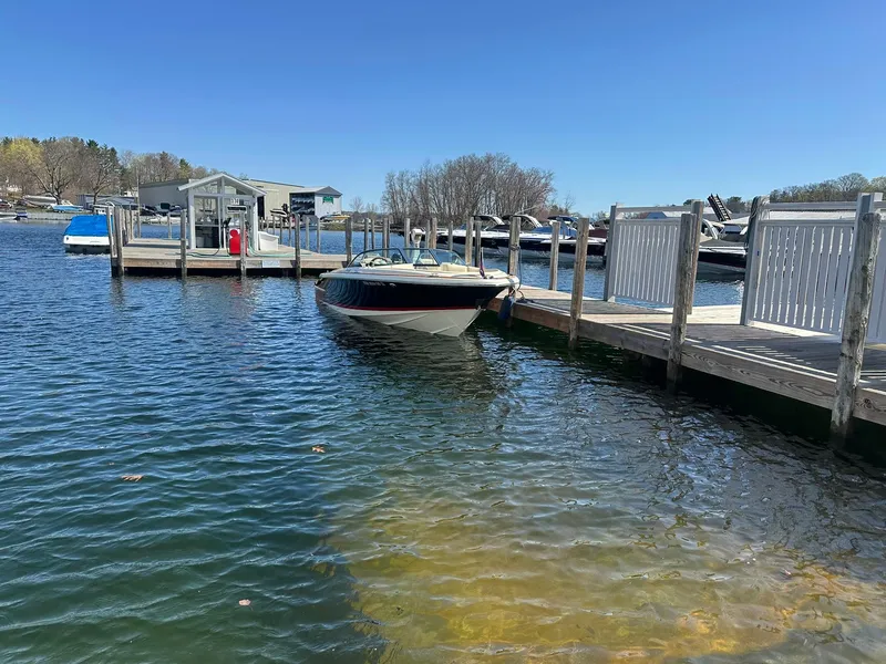 Slide: The Image of 2022 Chris-Craft Launch 23 boat docked at a serene marina under clear blue skies. - 3