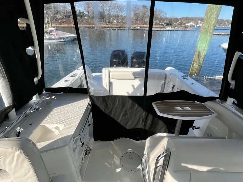 Slide: The Image of 2017 Boston Whaler 270 Vantage boat interior with seating and table, overlooking a serene waterfront. - 7