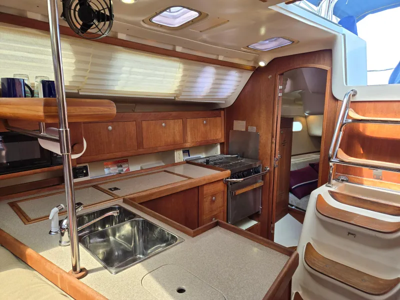 Slide: The Image of Interior of 2002 Hunter 380 sailboat with wooden cabinetry and modern kitchen amenities. - 10