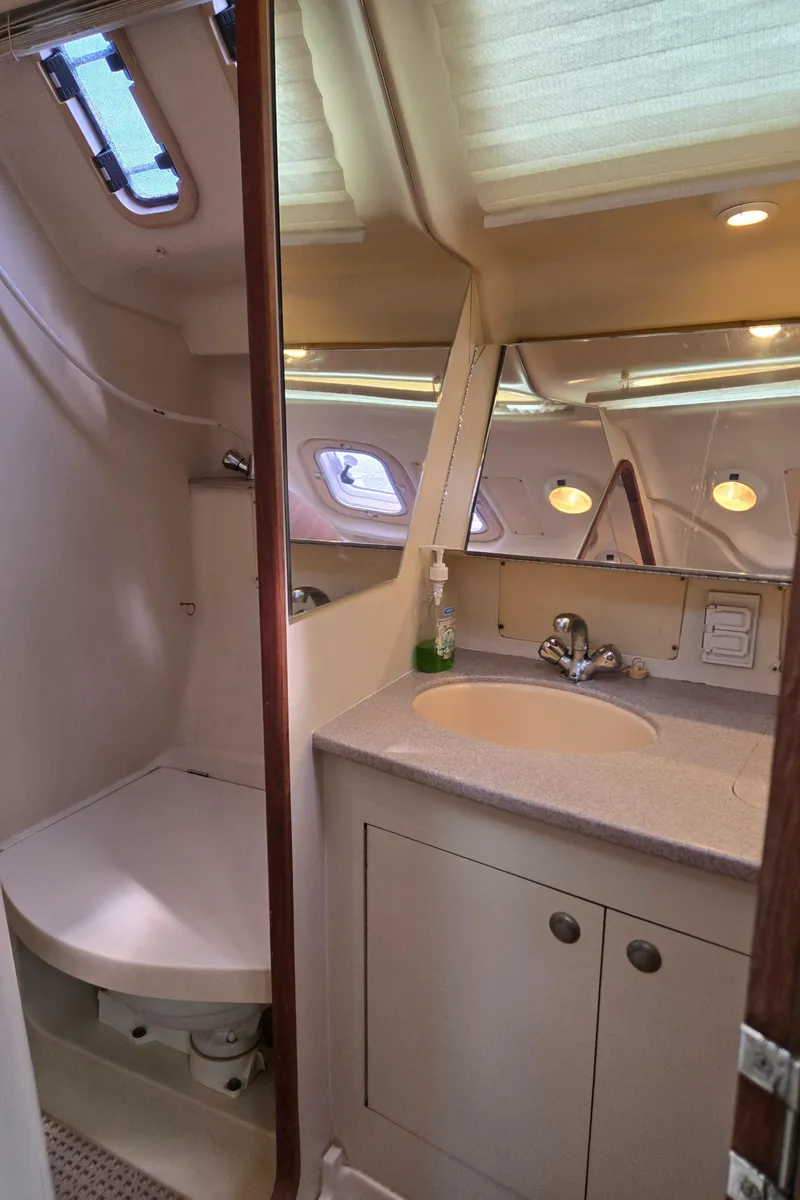 Slide: The Image of 2002 Hunter 380 yacht bathroom with sink, mirror, and porthole windows. - 21