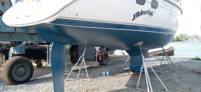 Slide: The Image of 2002 Hunter 380 sailboat on stands, displayed outdoors near water. - 28