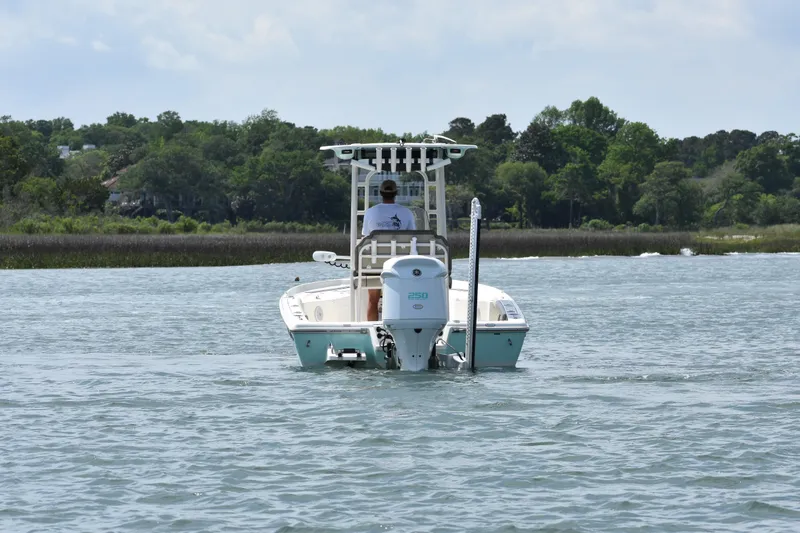 Slide: The Image of 2021 Key West 230 BR boat cruising on a calm lake with lush green shoreline. - 5