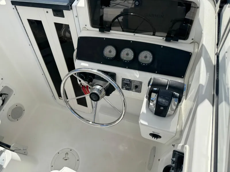 Slide: The Image of 1999 Boston Whaler Conquest 23 helm with steering wheel and control panel. - 10