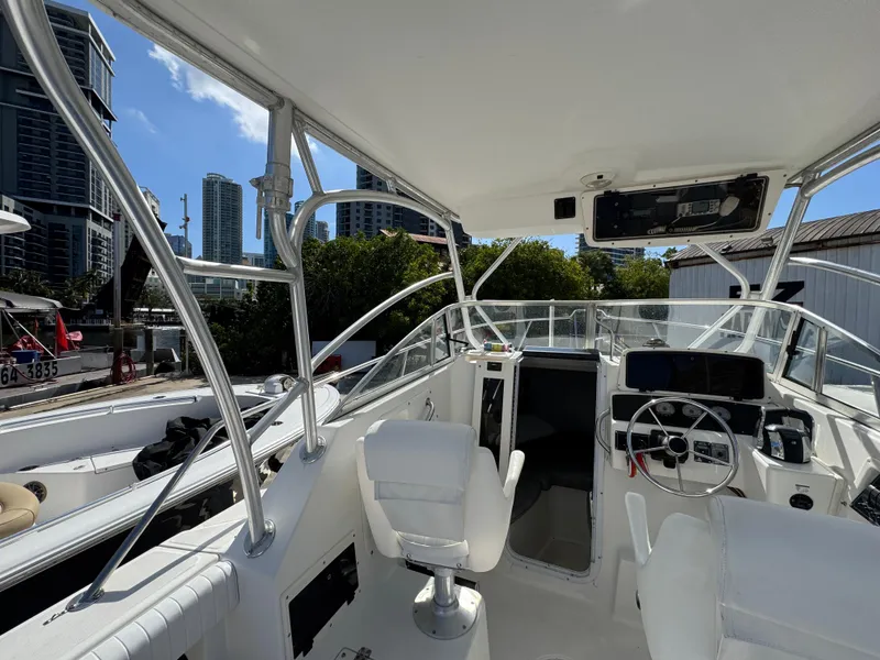 Slide: The Image of 1999 Boston Whaler Conquest 23 boat interior with steering wheel and city skyline background. - 18