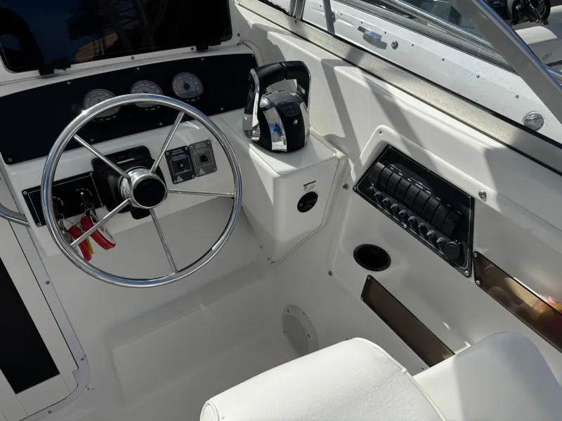 Slide: The Image of 1999 Boston Whaler Conquest 23 helm with steering wheel and control panel. - 19