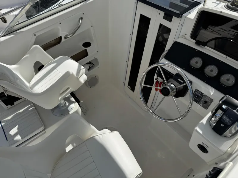 Slide: The Image of 1999 Boston Whaler Conquest 23 cockpit with steering wheel and white seating. - 20