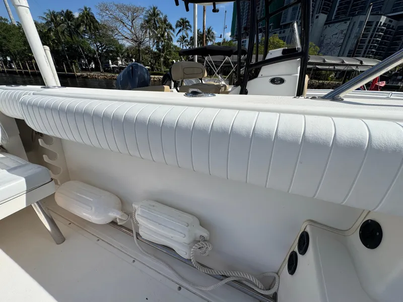 Slide: The Image of 1999 Boston Whaler Conquest 23 boat interior with white cushioned seating and docked in a marina. - 29