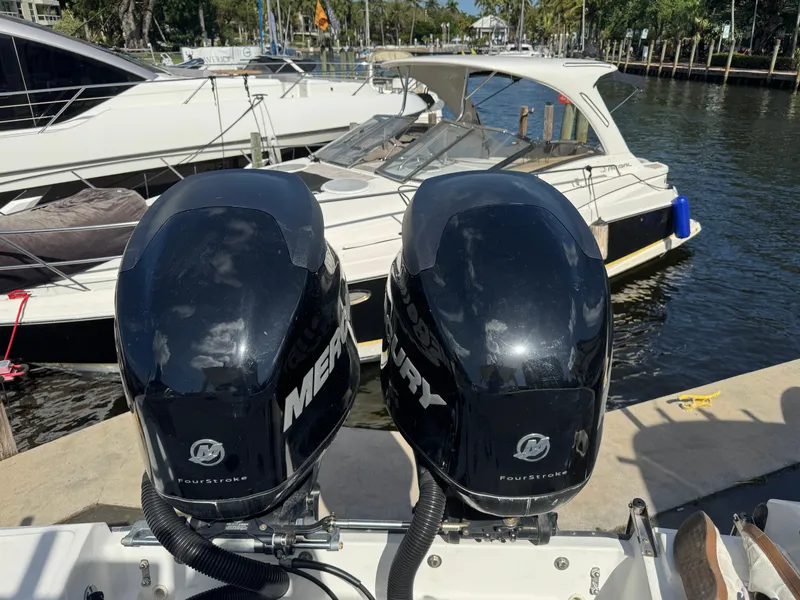 Slide: The Image of Twin Mercury outboard engines on a 1999 Boston Whaler Conquest 23 docked by the water. - 38