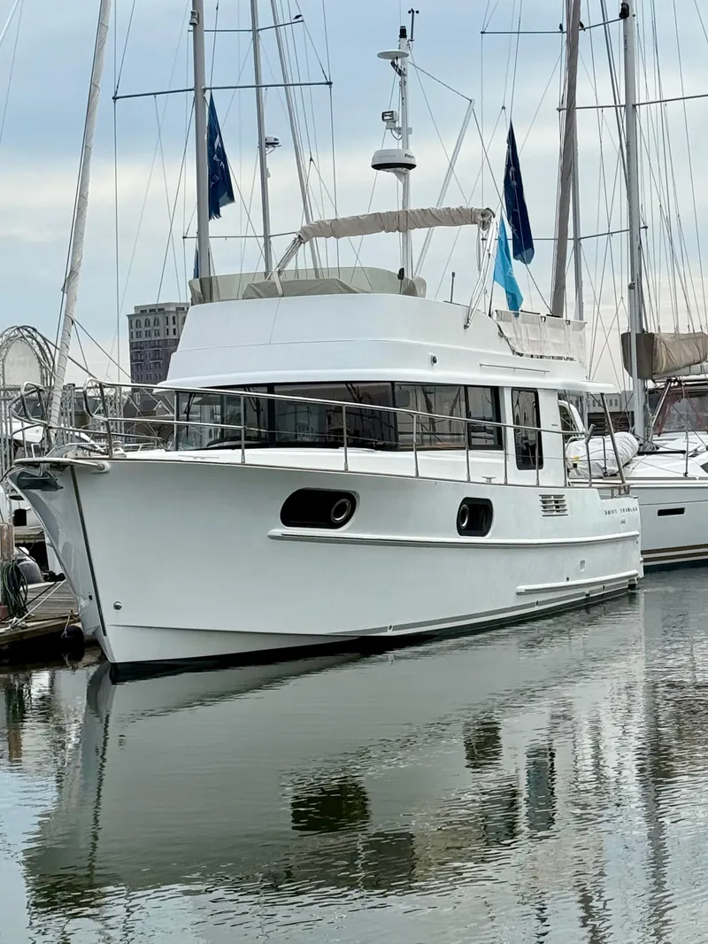 Slide: The Image of 2020 Beneteau Swift Trawler 44 docked in a marina, reflecting on calm water. - 0