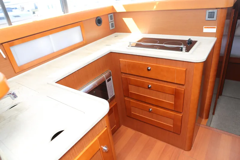 Slide: The Image of Interior of 2020 Beneteau Swift Trawler 44 kitchen with stove and wooden cabinetry. - 3