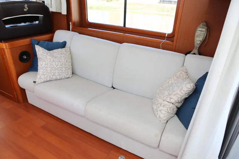Slide: The Image of Interior of 2020 Beneteau Swift Trawler 44 with white sofa and decorative pillows. - 8