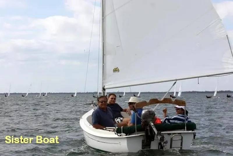 Slide: The Image of 2001 Com-Pac Picnic Cat sailboat with passengers on a calm sea. - 12