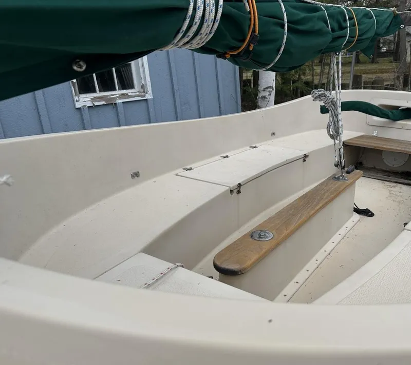 Slide: The Image of 2001 Com-Pac Picnic Cat sailboat interior with green sail cover and wooden bench. - 7