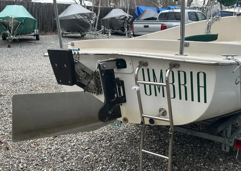 Slide: The Image of 2001 Com-Pac Picnic Cat sailboat with "UMBRIA" lettering, parked on gravel. - 8