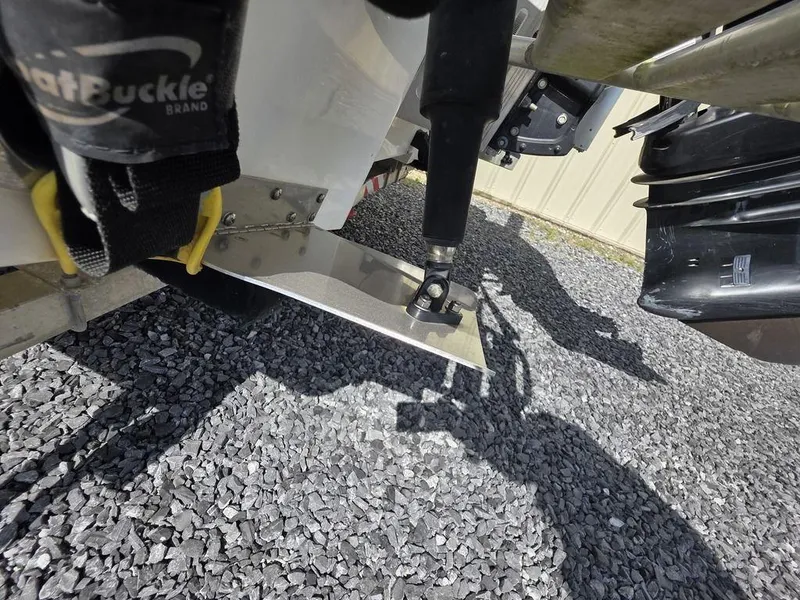 Slide: The Image of 2008 Blazer Bay 2420 Professional boat motor and trim tab on gravel surface. - 17