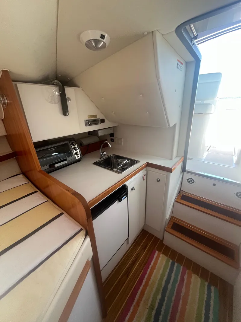 Slide: The Image of 2007 Tiara Yachts 2900 Coronet interior with kitchenette, striped rug, and wooden accents. - 28