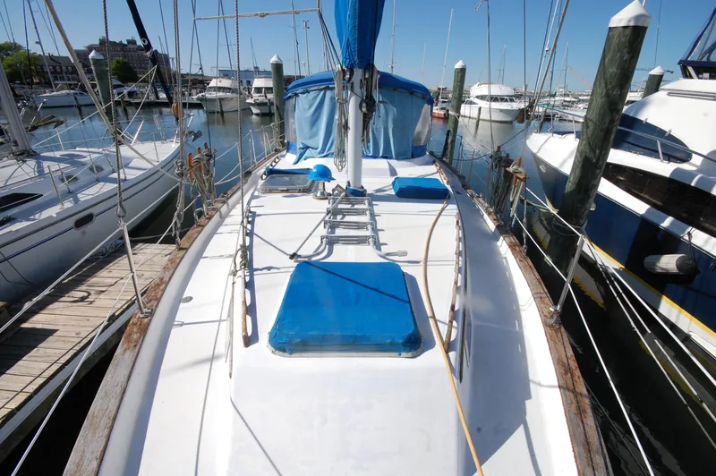Slide: The Image of 1981 Endeavour 40 sailboat docked in a marina, featuring a clean deck and blue covers. - 10