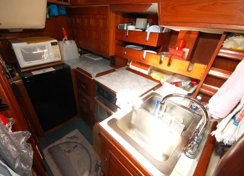 Slide: The Image of 1981 Endeavour 40 yacht galley with sink, microwave, and wooden cabinetry. - 19