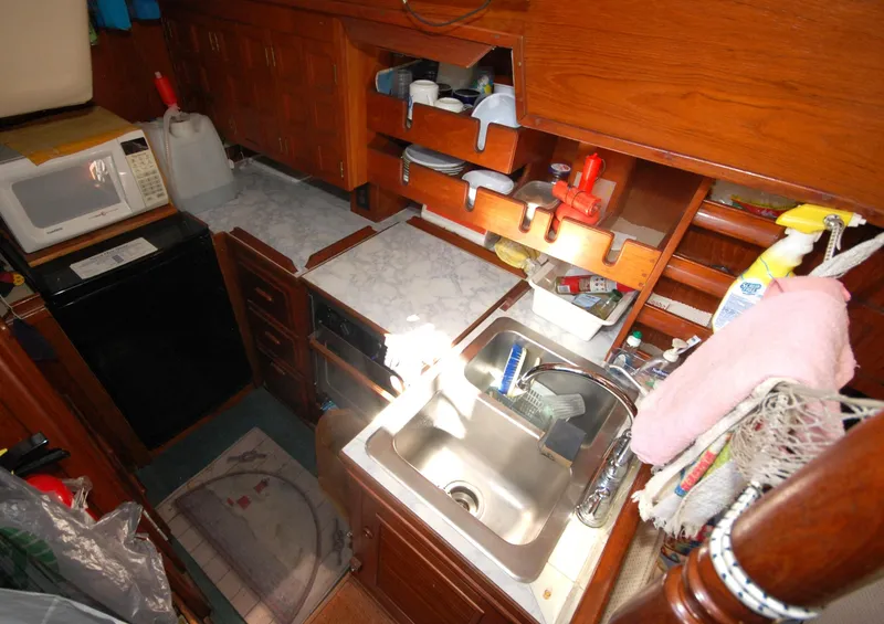 Slide: The Image of Compact kitchen area in a 1981 Endeavour 40 sailboat, featuring a sink, microwave, and storage. - 20