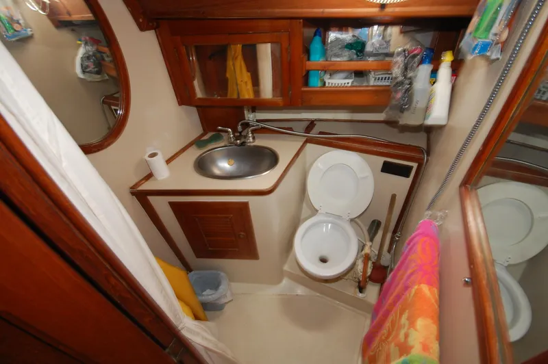 Slide: The Image of Compact bathroom in a 1981 Endeavour 40 yacht, featuring sink, toilet, and storage shelves. - 28