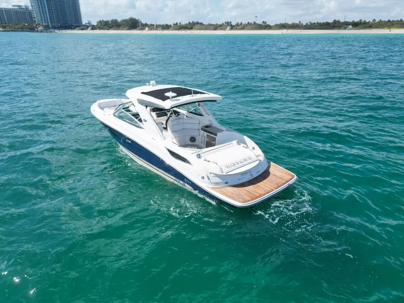 Slide: The Image of 2015 Sea Ray 350 SLX boat cruising on clear blue water near a sandy shoreline. - 21