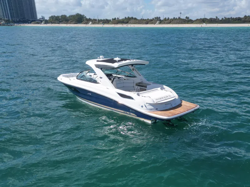 Slide: The Image of 2015 Sea Ray 350 SLX boat cruising on clear blue water near a sandy shoreline. - 22