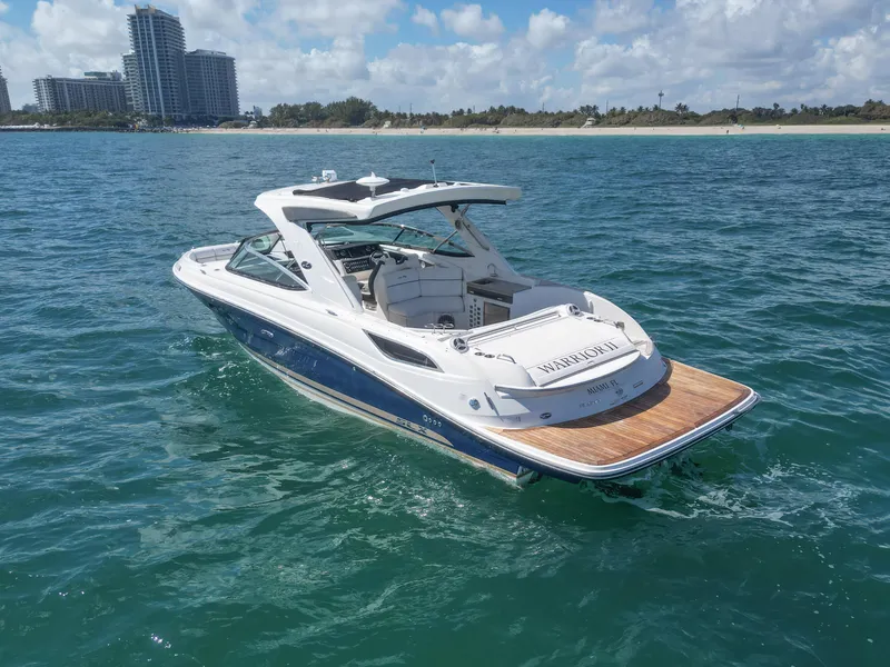 Slide: The Image of 2015 Sea Ray 350 SLX boat cruising on clear blue water near a city shoreline. - 24