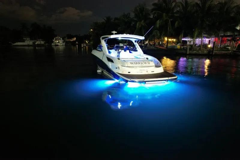 Slide: The Image of 2015 Sea Ray 350 SLX boat illuminated by blue underwater lights at night. - 6