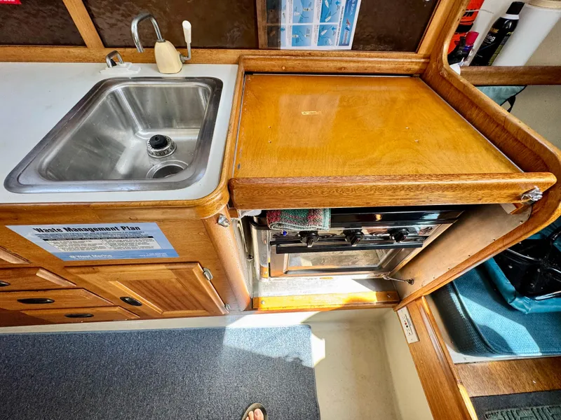 Slide: The Image of 1970 CAL 29 yacht kitchen with sink, stove, and wooden cabinetry. - 12