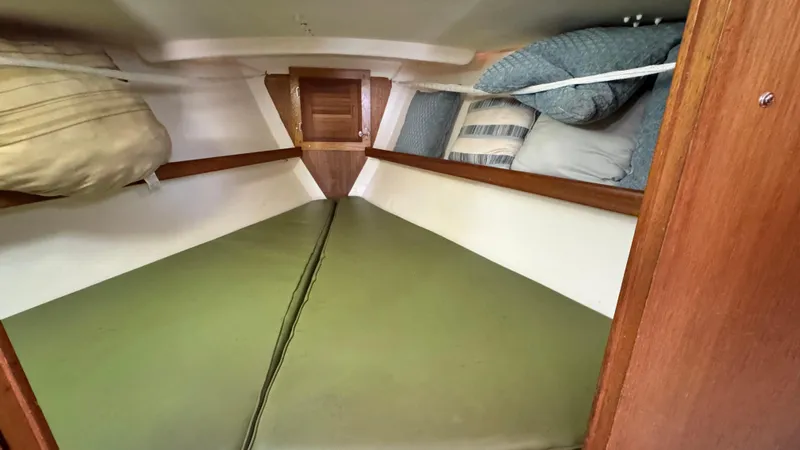 Slide: The Image of 1970 CAL 29 sailboat interior cabin with green cushions and wooden accents. - 17