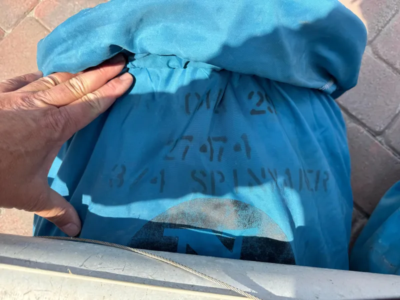 Slide: The Image of Blue fabric with stenciled numbers and letters, hand adjusting it, on a brick surface. - 20