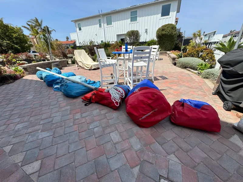 Slide: The Image of Sailing gear and bags on a patio, near a white house, under a clear sky. - 3