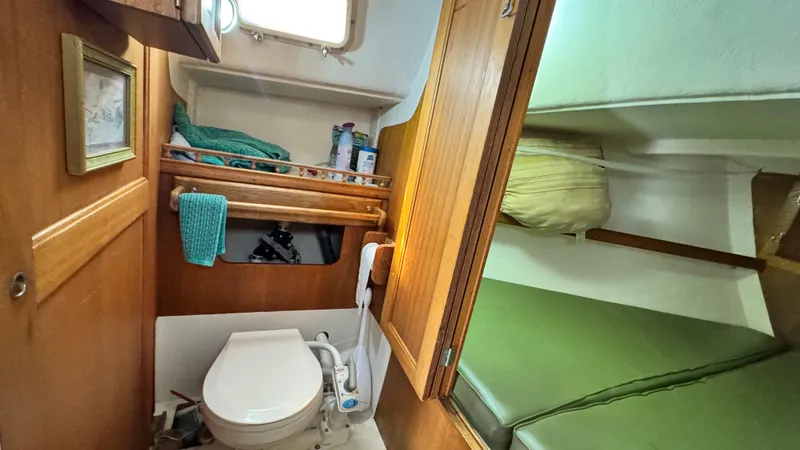 Slide: The Image of 1970 CAL 29 sailboat interior with compact bathroom and cozy sleeping area. - 7