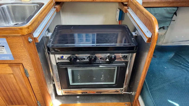 Slide: The Image of 1970 CAL 29 yacht kitchen with stove, oven, and wooden cabinetry. - 8