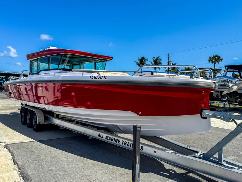 Slide: The Image of 2023 Axopar 37 XC CROSS CABIN boat on trailer, vibrant red hull, sunny day. - 2